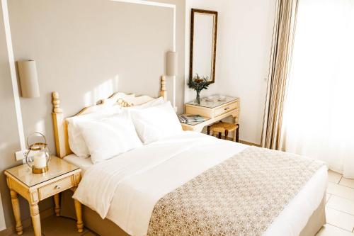 a white bedroom with a bed and a mirror at Pelican Hotel in Mýkonos City