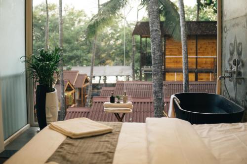a room with a bed and a large window at Tranquill Riverside Luxury Cottages With Bathtub, Candolim in Candolim