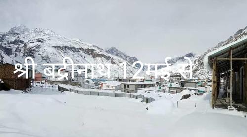 een met sneeuw bedekte berg met een skigebied met een gebouw bij House by Prithvi Yatra Hotel in Badrīnāth