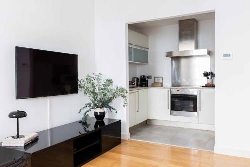 a white kitchen with a flat screen tv on a wall at Cosy 1 Bed Apartment in the heart of Mayfair! in London