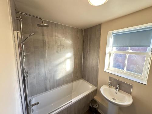 a bathroom with a shower and a sink and a tub at Meadowside Apartment in Filey