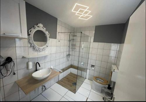 a bathroom with a sink and a toilet and a mirror at obermaubach-am see Apartments in Kreuzau