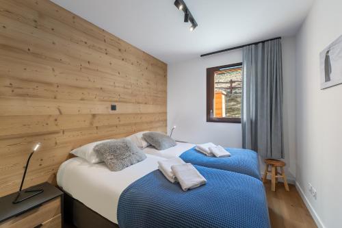 two beds in a bedroom with a wooden wall at Quintessence - Apt A201 - BO Immobilier in Châtel