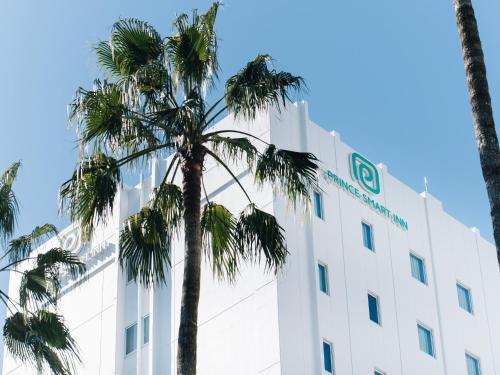 a palm tree in front of a white building at Prince Smart Inn Miyazaki in Miyazaki