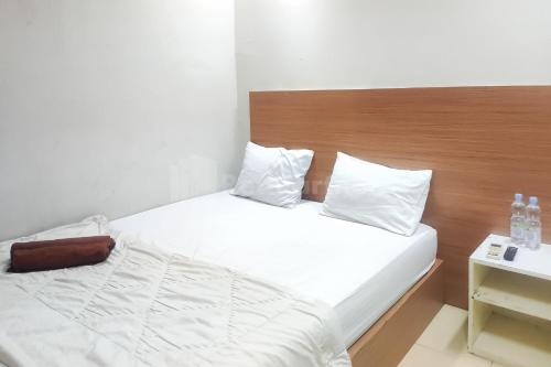 um quarto com uma cama branca e uma cabeceira em madeira em Tebet Glory House Mitra RedDoorz em Jakarta