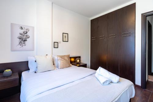 a bedroom with a white bed and a brown cabinet at Harbor Apartments in Larnaca in Larnaka