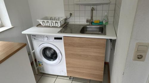 een kleine keuken met een wastafel en een wasmachine bij Jonagold Unterkunft in Karlsruhe