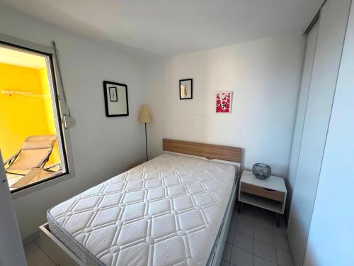 une petite chambre avec un lit et une fenêtre dans l'établissement SAVANNA BEACH I Joli 2 pièces cabine vue mer piscine Rochelongue Cap d'Agde, au Cap d'Agde