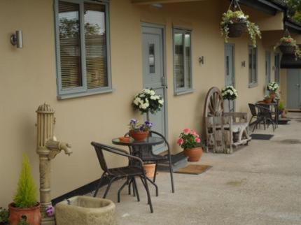 a patio with chairs and a table and a building at The Stables - Deer Park Farm in Solihull