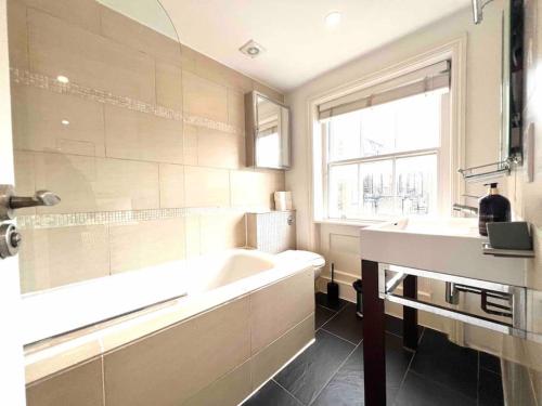 baño con bañera, lavabo y ventana en Hyde Park- 1 Bed en Londres