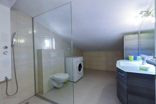 ein Badezimmer mit einem WC und einer Waschmaschine in der Unterkunft Strandnahes Apartment mit Pool, Whirlpool in Klenovica