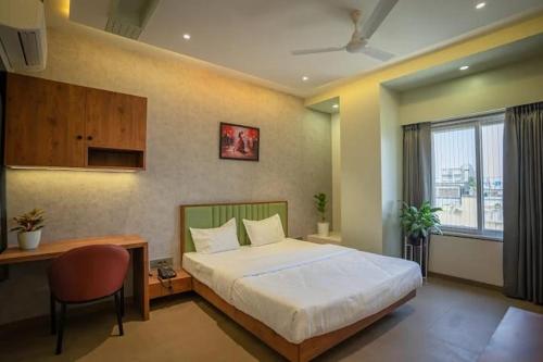 1 dormitorio con 1 cama grande, escritorio y ventana en Hotel Amar Palace Ahmednagar en Ahmadnagar