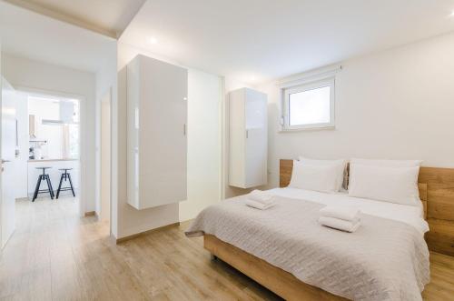 een witte slaapkamer met een groot bed met witte kussens bij Luxusapartment mit Pool, Sauna, direkt am Meer in Novi Vinodolski