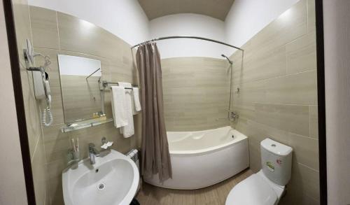 a bathroom with a tub and a sink and a toilet at HOTEL ARAL in Nukus