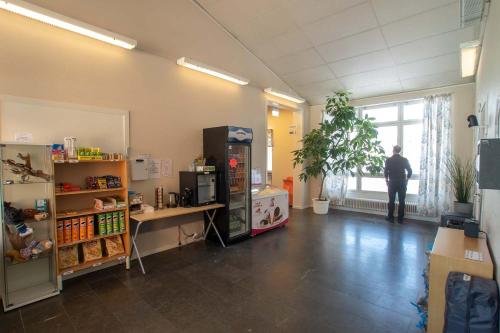 a room with a refrigerator and a person looking out the window at Dalasjö vandrarhem in Vilhelmina