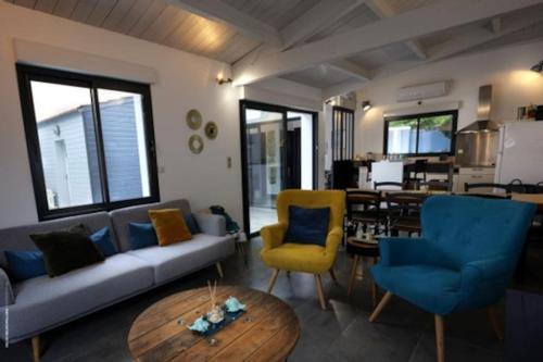 ein Wohnzimmer mit einem Sofa, Stühlen und einem Tisch in der Unterkunft Villa Maurice avec piscine centre La Rochelle in La Rochelle