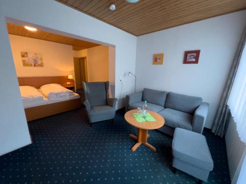 une chambre d'hôtel avec un canapé, une table et un lit dans l'établissement Hotel Haus Christel, à Willingen