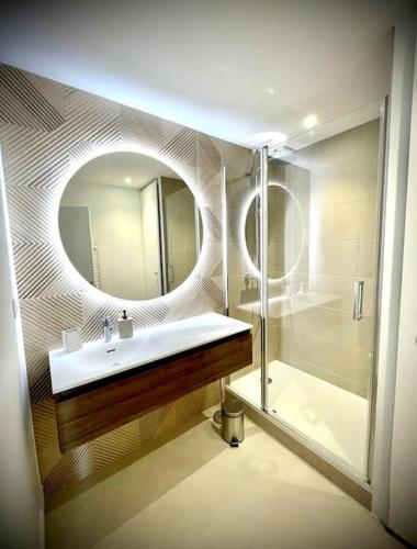 une salle de bain avec un lavabo, un miroir et une douche dans l'établissement Vue mer La Baule : Le Carina, à La Baule
