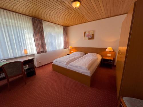 a hotel room with a bed and a desk and window at Hotel Haus Christel in Willingen
