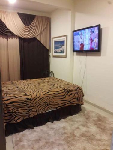 um quarto com uma cama e uma televisão na parede em Casa no Rio de Janeiro