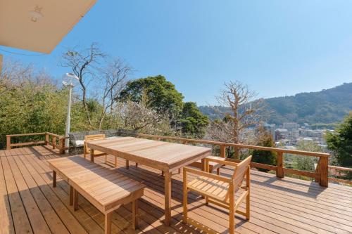 a wooden deck with a wooden table and benches at Ryokan -Suikoen- in Yugawara