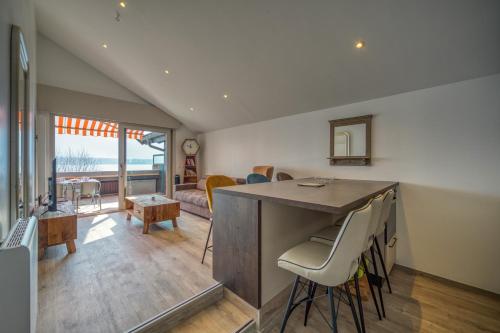 une cuisine et un salon avec une table et des chaises dans l'établissement Rooftop pieds dans l’eau, terrasse, parking sécu, au Bourget-du-Lac