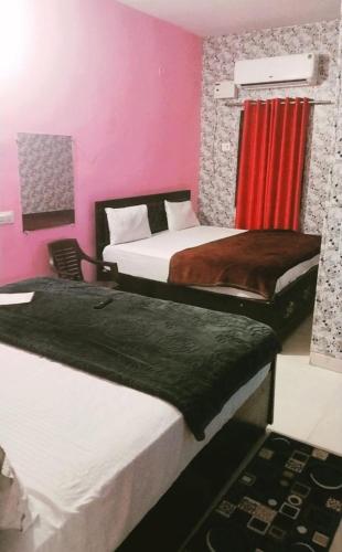 two beds in a room with pink walls at Premshi Guest House in Ayodhya