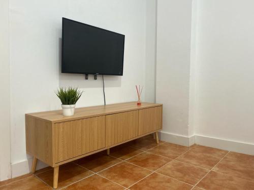 TV de pantalla plana en la parte superior de un armario de madera en Apartamento Valdepasillas, en Badajoz