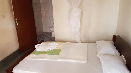 białe łóżko z 2 poduszkami w pokoju w obiekcie LA PLANETTE LODGE & BAR w mieście Gisenyi