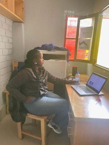 LA PLANETTE LODGE & BAR في جيسايني: امرأة تجلس في مكتب مع جهاز كمبيوتر محمول