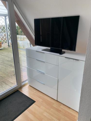 a white dresser with a television on top of it at Über den Dächern der Stadt in Bremervörde