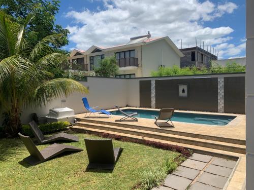 un patio trasero con sillas y una piscina en Mungur villa, en Flic en Flac