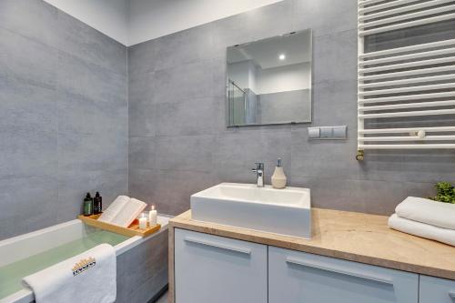 Nad Stawem by Downtown Apartments في غدانسك: حمام مع حوض أبيض ومرآة