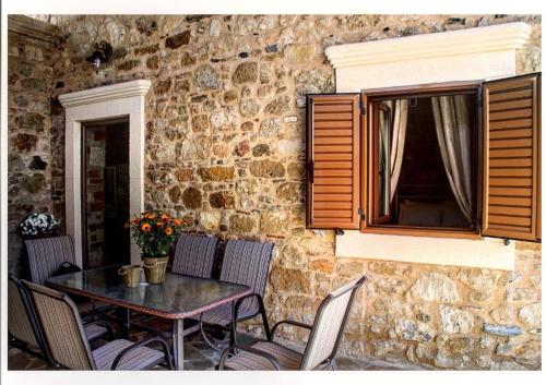 a table and chairs in front of a stone wall at M&M STONE-Village House-Family-Vintage in Líndos