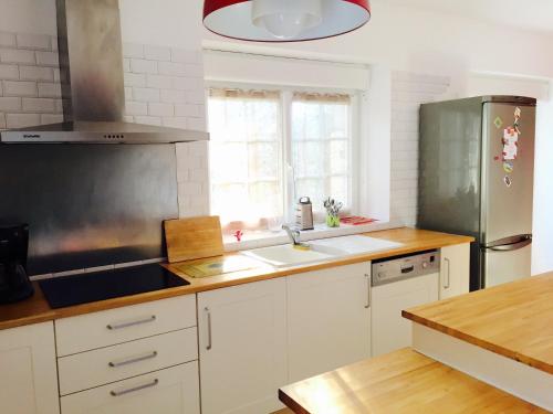 une cuisine avec des armoires blanches et un réfrigérateur en acier inoxydable dans l'établissement Maison Coeur Nature pres du zoo beauval, à Châtillon-sur-Cher