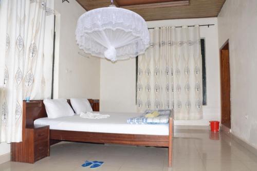 a bedroom with a bed with a chandelier and a window at GARDEN INN by AIRPORT inn ltd in Kigali
