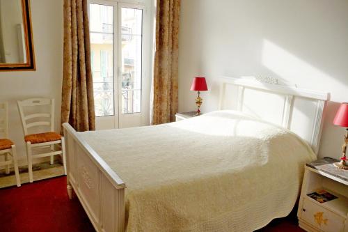- une chambre avec un lit blanc et une fenêtre dans l'établissement Magenta, à Menton