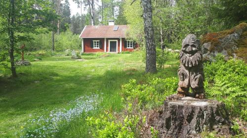 Una statua seduta su un ceppo di fronte a una casa di Kvarnamo a Ökna