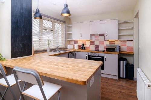 a kitchen with white cabinets and a wooden counter top at Banchory House - SJA Stays - 2 Bed Apartment in Banchory