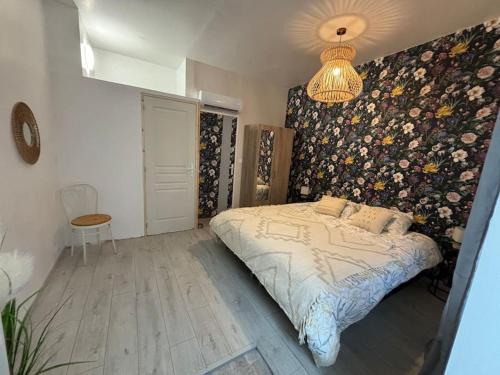 1 dormitorio con 1 cama con pared de flores en Le studio «des Terroux », 