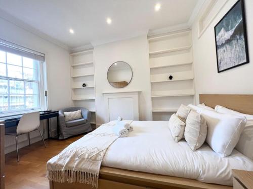 1 dormitorio con cama, escritorio y espejo en Split Level 3 Bed- Hyde Park, en Londres