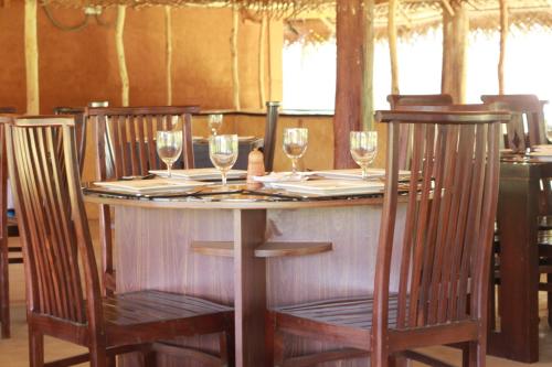 a table with four chairs and wine glasses on it at Cabanas by Cloudz Sigiriya in Sigiriya