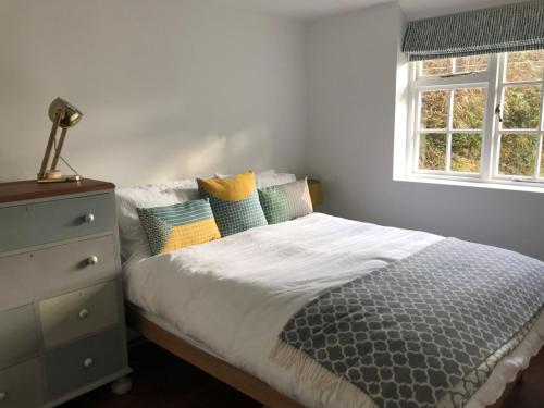 1 dormitorio con 1 cama con tocador y ventana en Old Cottage, Crackington Haven, North Cornwall, en Bude