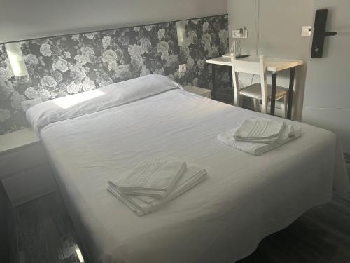 Una cama blanca con dos servilletas encima. en casa julian-inn, en Madrid