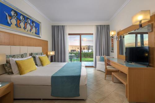 a hotel room with a bed and a desk and a television at Lindos Imperial Resort & Spa in Kiotari