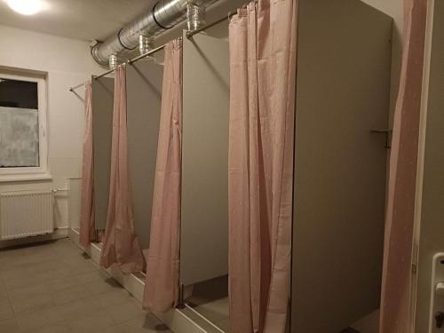 a row of pink shower curtains in a bathroom at Ubytovňa Nobelova in Bratislava