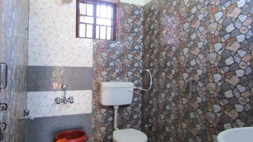 a bathroom with a toilet and a sink and a window at Mahabala Valley Guest House in Gokarna