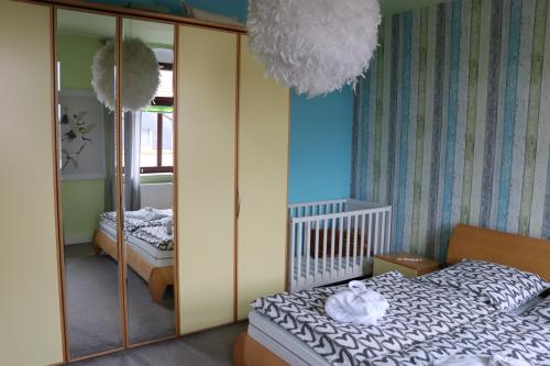 een slaapkamer met een bed, een spiegel en een wieg bij XXL Ferienliebe in Habrachćicy