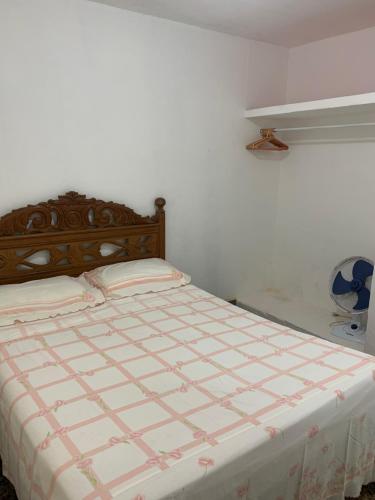 a bed in a white room with a bedspread on it at Casa na praia do centro in Marataizes