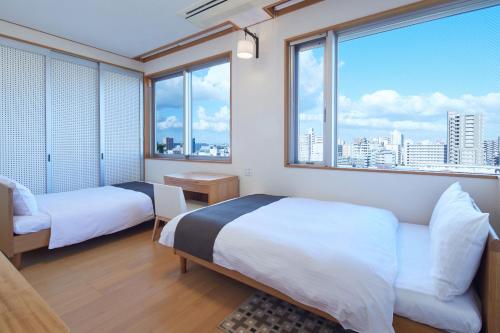 厚木市にあるRembrandt Atsugi BETTEI サウナ&無煙ロースター付き12名定員のベッド2台と大きな窓が備わるホテルルームです。
